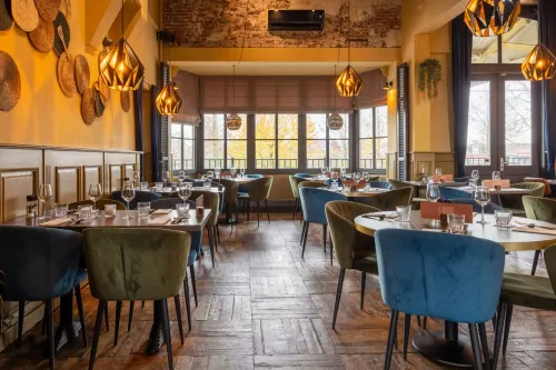 Een overzichtsfoto van het restaurant met tafels en gekleurde stoelen.