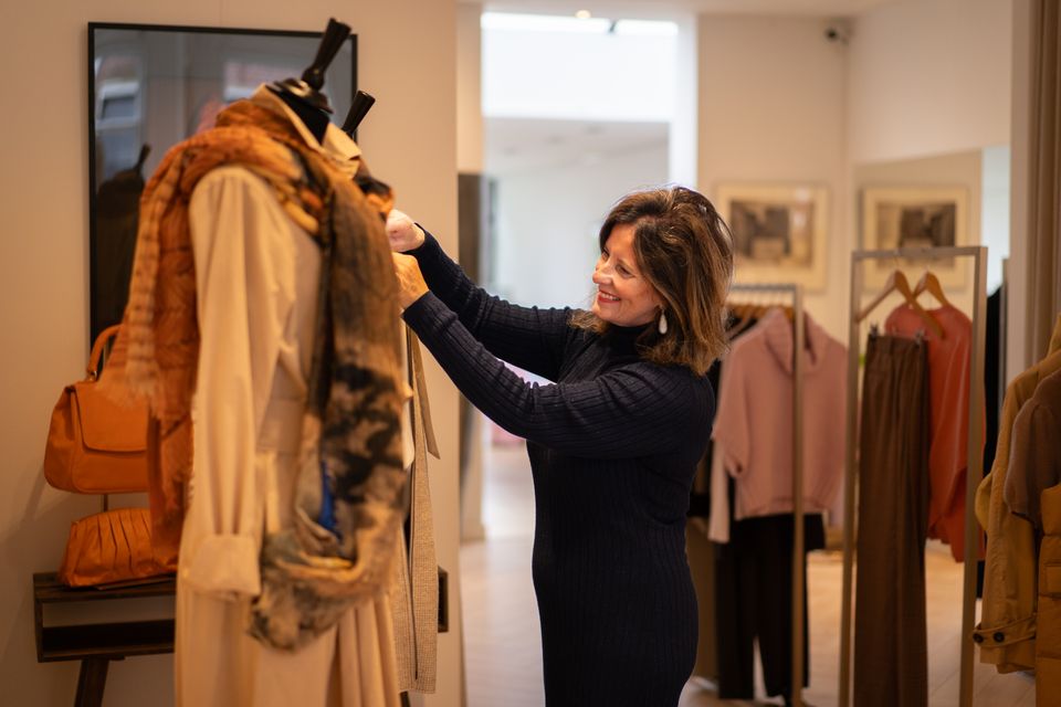 Een vrouw die kleding aan het ophangen is in een kledingwinkel