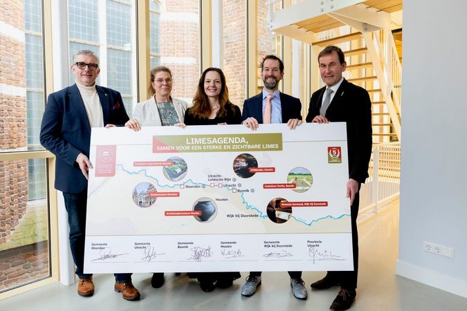 Vier personen houden een grote kaart van de Limes vast.