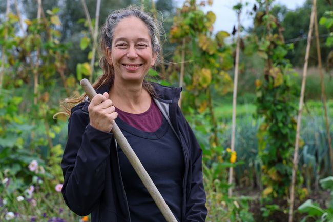 Een glimlachende vrouw staat tussen planten op een boerderij.