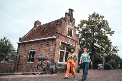 Historisch pand in IJsselstein, Groene Hart, twee vrouwen wandelen door het oude centrum langs een karakteristiek bakstenen gebouw met trapgevel. Fotografie: Studio Chanou.