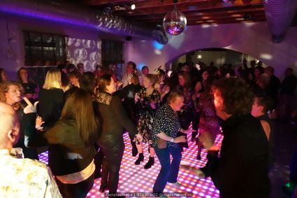 Bezoekers dansen op een verlichte dansvloer onder een discobal tijdens Danskasteel in Kasteel Woerden, een feest met hits uit de jaren 70, 80, 90 en zeroes.