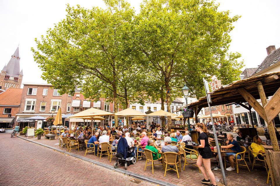Een foto door VisitBrabant van de volle terrassen op de Ginnekenmarkt van Breda