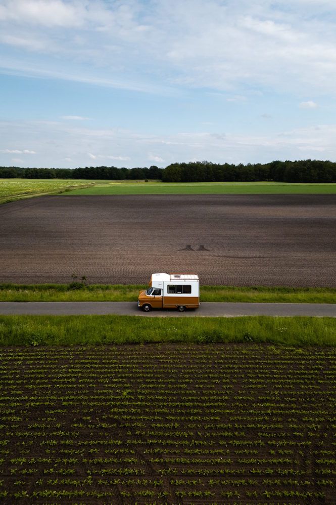 Een camper rijdt door het landschap in Drenthe.