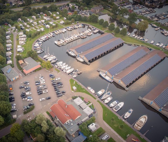 Luchtfoto van Jachthaven Camping De Domp in Sneek met boten in het water en caravans en campers op het campingveld.