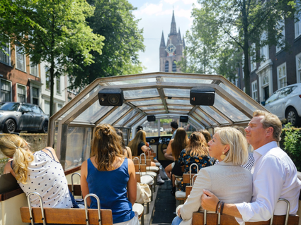 Mensen zitten op de rondvaart boot in Delft kijkend naar de Oude Kerk