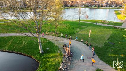Sportieve groepsactiviteit Paaswork-out bij Sportsaeck in Woerden, Groene Hart, met deelnemers die samen buiten trainen en oefeningen doen langs het water in een groen park.