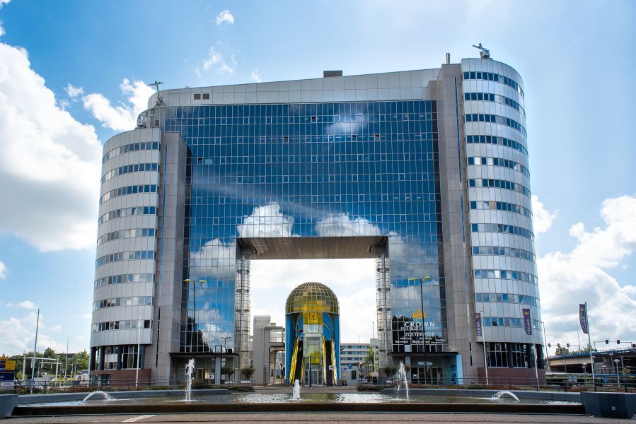 De voorkant van de Mandelabrug van een afstand. Je ziet een groot gebouw wat is ontworpen boven de brug en een mooie fontein.