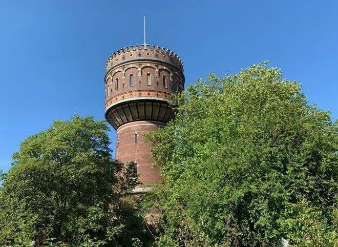 De Watertoren die tussen de groene bomen uitsteekt