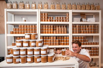 Interieur met potten pindakaas en winkelmedewerker van de Pindakaaswinkel in Leiden