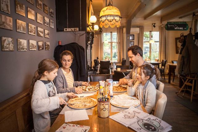 Een gezin die pannenkoeken zitten te eten bij Pannenkoekenrestaurant De Witte Swaen