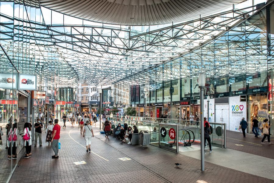 Binnen in het overdekte gedeelte van het stadshart met veel mensen en veel winkels.