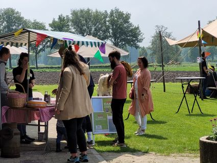 Groepje mensen bij een kraam op de wei van Koeientuin Tierelier