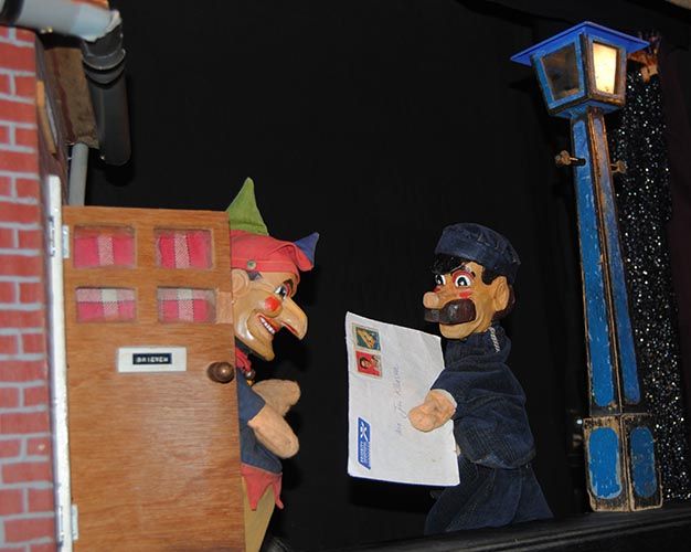 Foto van de poppen Jan Klaassen die achter een deur staat en een postbode met een brief voor Jan Klaassen.