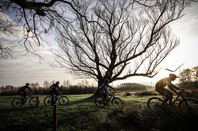 Mountainbikers racen achter elkaar aan door het Drentse landschap.