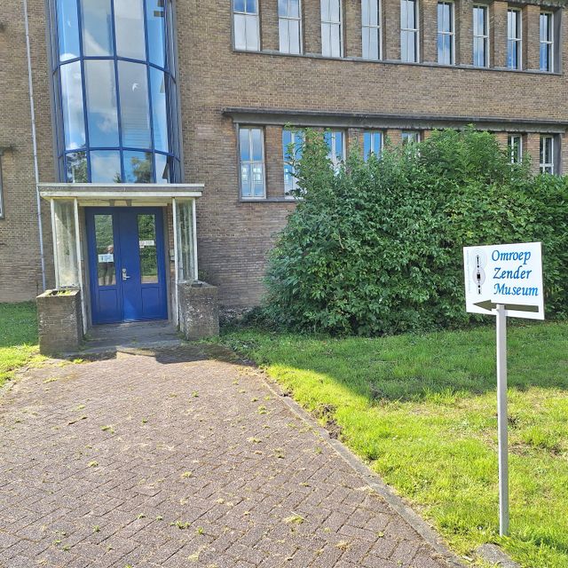 Museum Omroep Zender Museum in Lopik, Groene Hart. Entree van het museum met bewegwijzering, karakteristiek bakstenen gebouw en toegangspad bij de historische zendlocatie.