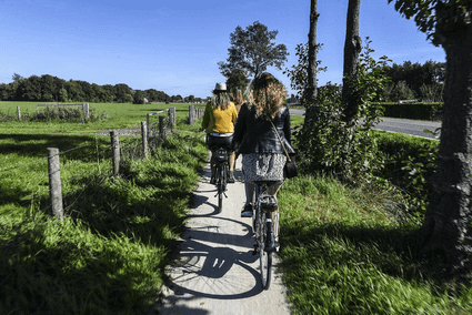 Dames fietsen door de weilanden