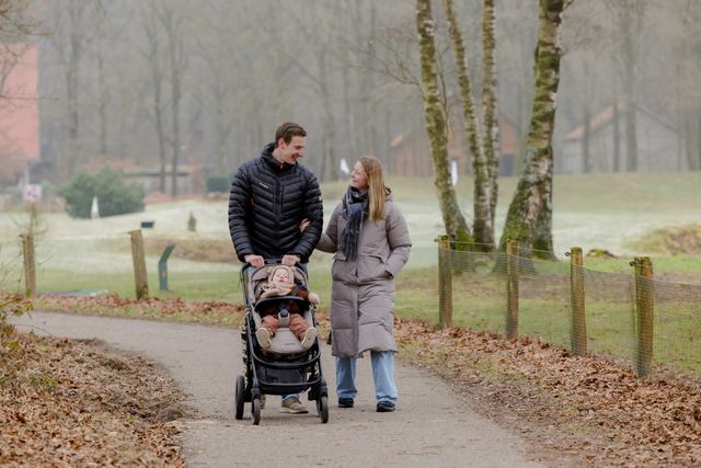 Man en vrouw wandelend met hun kind in de wandelwagen.