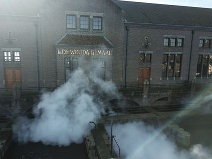 woudagemaal in gouden letters en stoom aan de voorkant van het gebouw