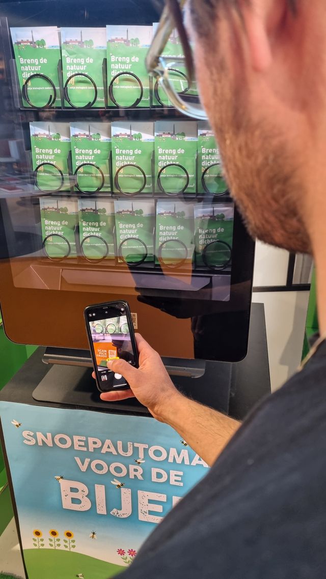 Foto van iemand die de QR-code op de bijenautomaat scant