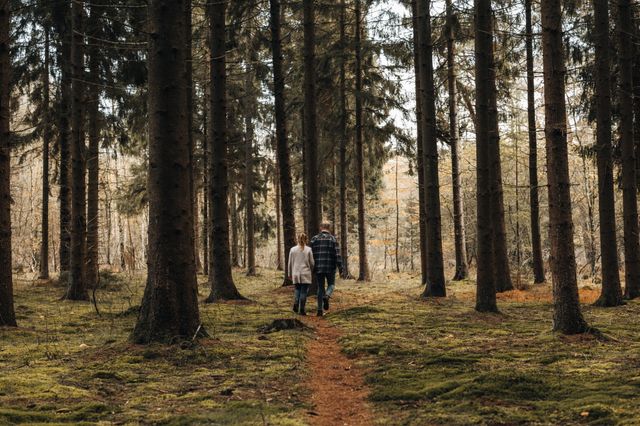 Een man en een vrouw wandelen door een bos met herfstkleuren.
