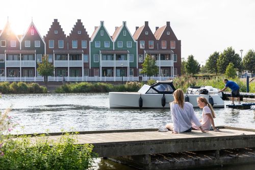 Een foto van het hotel op de achtergrond met bootjes en een moeder en dochter op de voorgrond