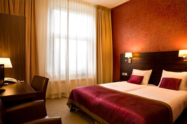 Een hotelkamer in hotel Kontakt der kontinenten met zacht licht en rode muren