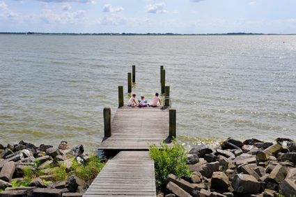 kinderen zitten op een steiger bij het water