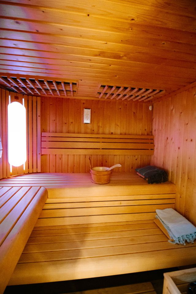 Holzbänke in einer Holzsauna mit Fenster zum Blick nach draußen.