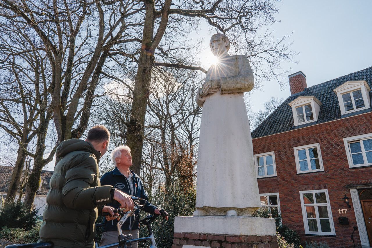 De zon schijnt van achter op het monument van Pastoor Bastiaansen