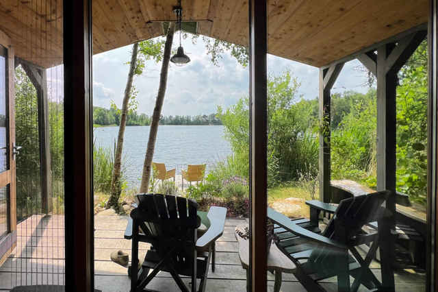 Ein Holzhaus am Wasser mit zwei einladenden Stühlen auf dem Steg beim Landgut Hendriksveen.