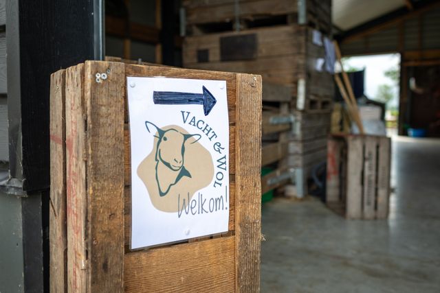Houten welkomstbord met logo van Vacht & Wol in Harmelen, uitnodigend voor bezoekers van de ambachtelijke wolwerkplaats, onderdeel van Hollandse Ambachten Utrecht Region.