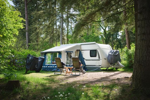Een caravan met twee mensen op campingstoeltjes bij Camping De Waps in Oudemirdum.