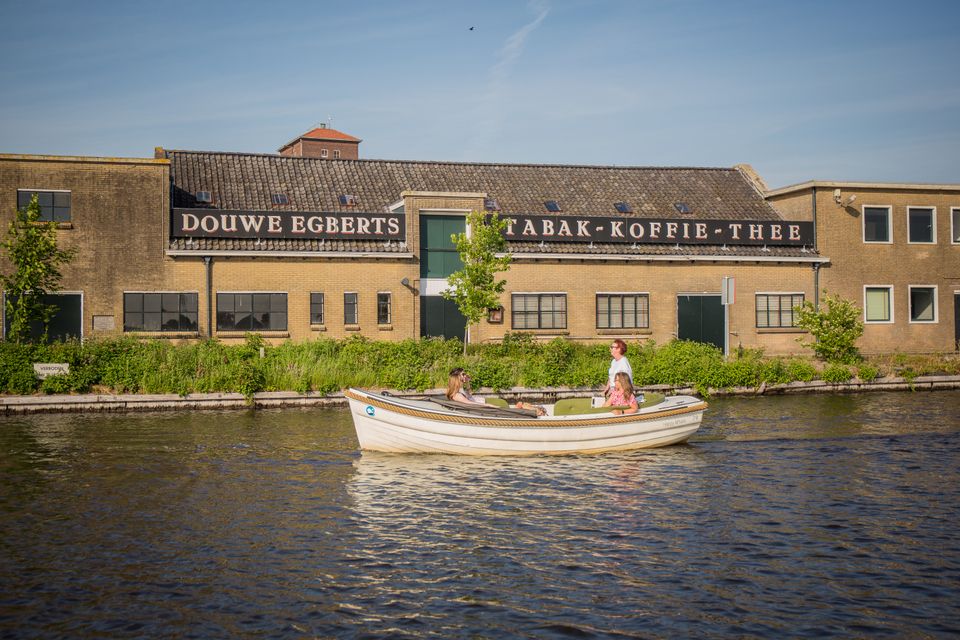 Sloep vaart langs de oude DE fabriek