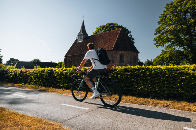 Een man fietst langs het Kerkje van Zweeloo dat Van Gogh schilderde.