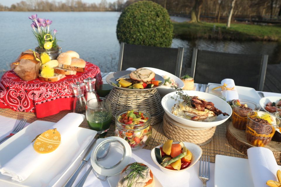 Landelijke buitenplaats, Buitenplaats Kameryck, Kamerik, Groene Hart, feestelijk gedekte tafel met paasbrunch aan het water met brood, vleesgerechten, salades en lentebloemen op het terras.