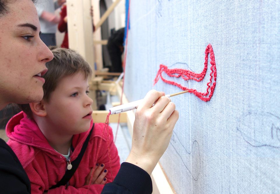 Een moeder met zoon die iets borduren