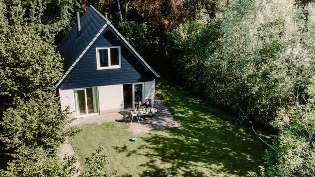 Een vakantiehuisje in het bos, van bovenaf gezien.