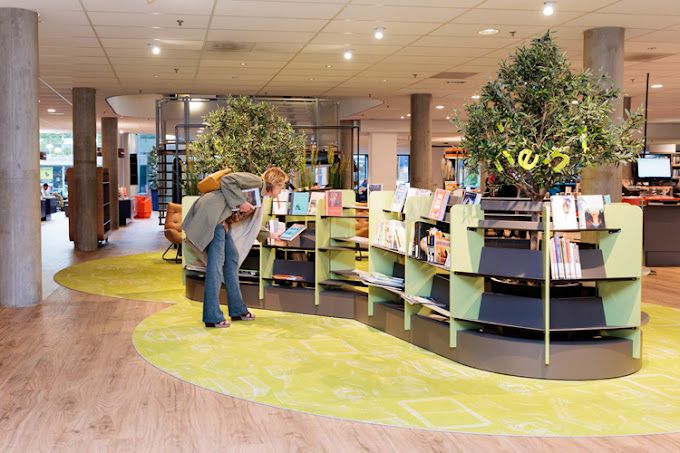 Een vrouw die een boek uitzoekt in de Bibliotheek Purmerend