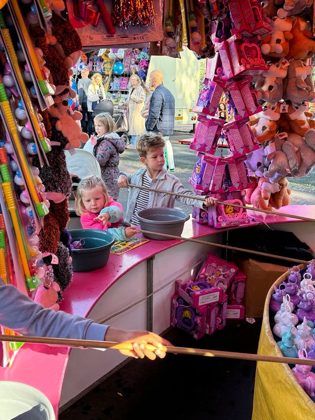 Een jong meisje en jonge jongen vissen eendjes op de kermis van de Jouster Merke