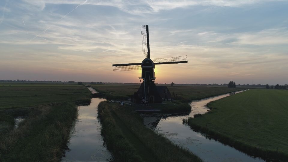 Uitzicht over de polder en de Cabauwse Molen met ondergaande zon