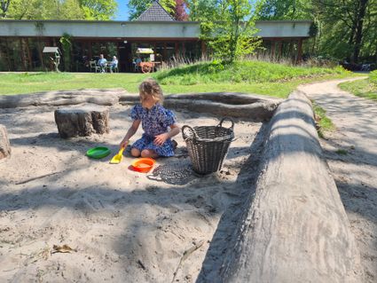 Meisje speelt in zandbak met op achtergond Groot Speijck