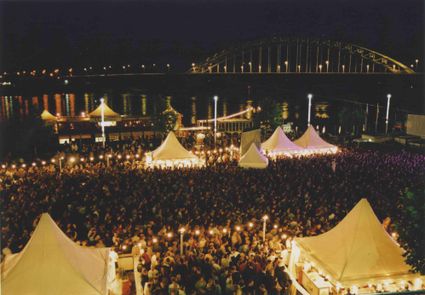 Beschrijving	32e Vierdaagsefeesten. Gezicht op het volle evenementenplein voor het Holland Casino op de slotavond met op de achtergrond de (verlichte) Waalbrug.
Datering	20/7/2001