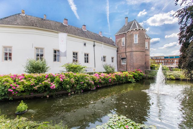 Historisch Kasteel Montfoort, Groene Hart. Monumentaal kasteel met ronde toren, gracht, fontein, bloeiende hortensia's en weerspiegeling in het water op een zonnige dag.