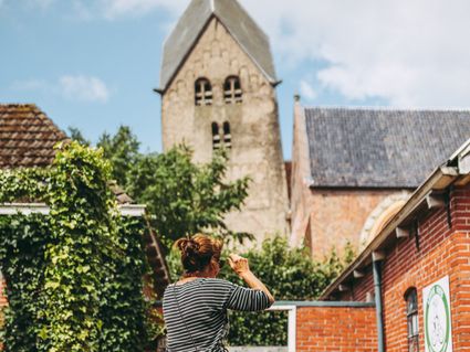 Een vrouw die een foto maakt van de Walfriduskerk in Bedum