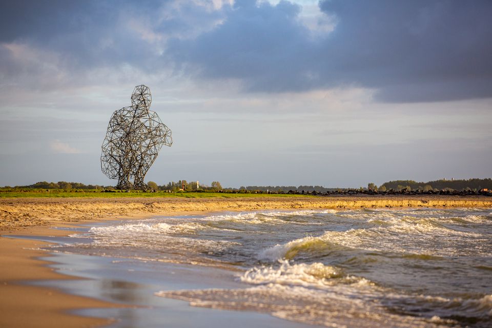 Kunstwerk hurkende man met water op voorgrond.