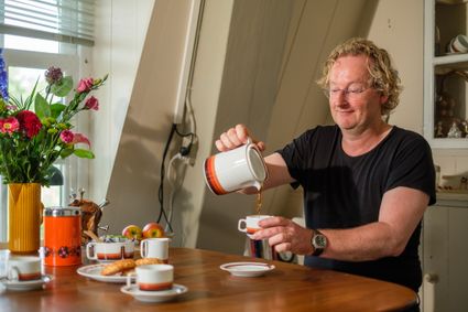De molenaar zit aan tafel en schenkt een kopje koffie in.