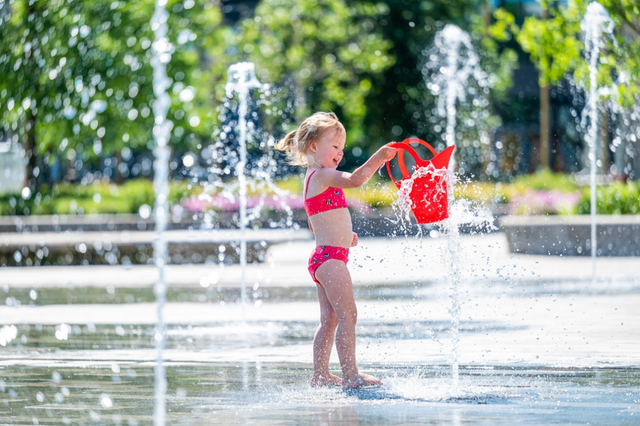 Ein Mädchen spielt mit einer Gießkanne und Wasser auf einem Platz in Drenthe.