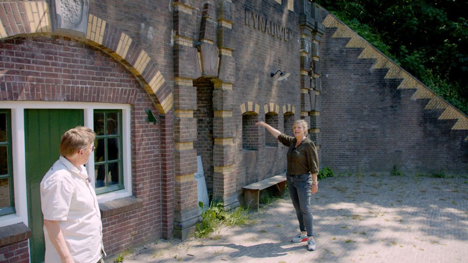 Twee vrouwen staan buiten bij een bakstenen fort.