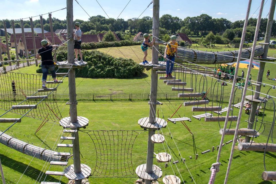 Kinder klettern über einen Parcours in einem Kletterpark.